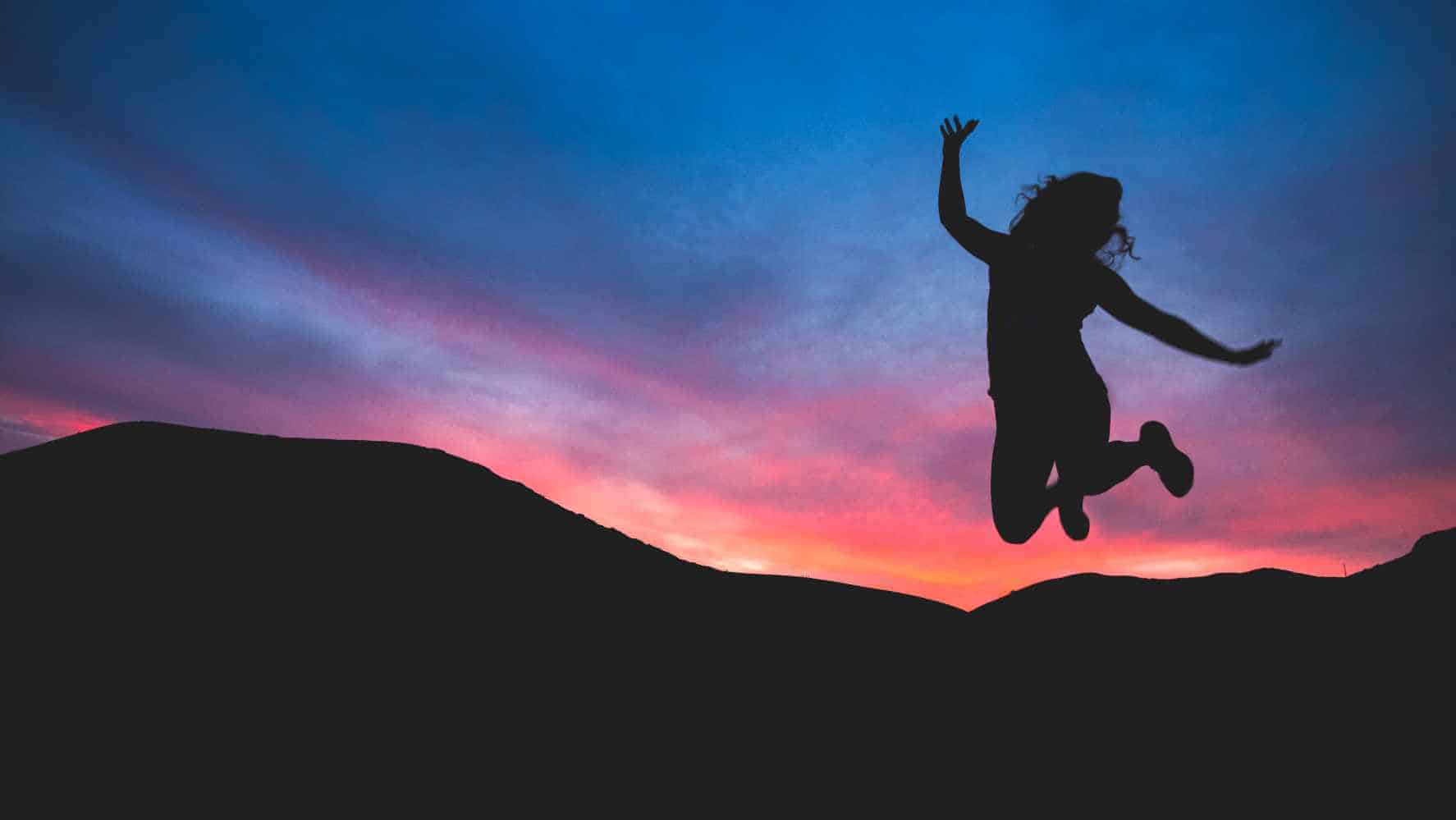 A person jumping in the air with a sunrise background to show benefits of counselling / therapy