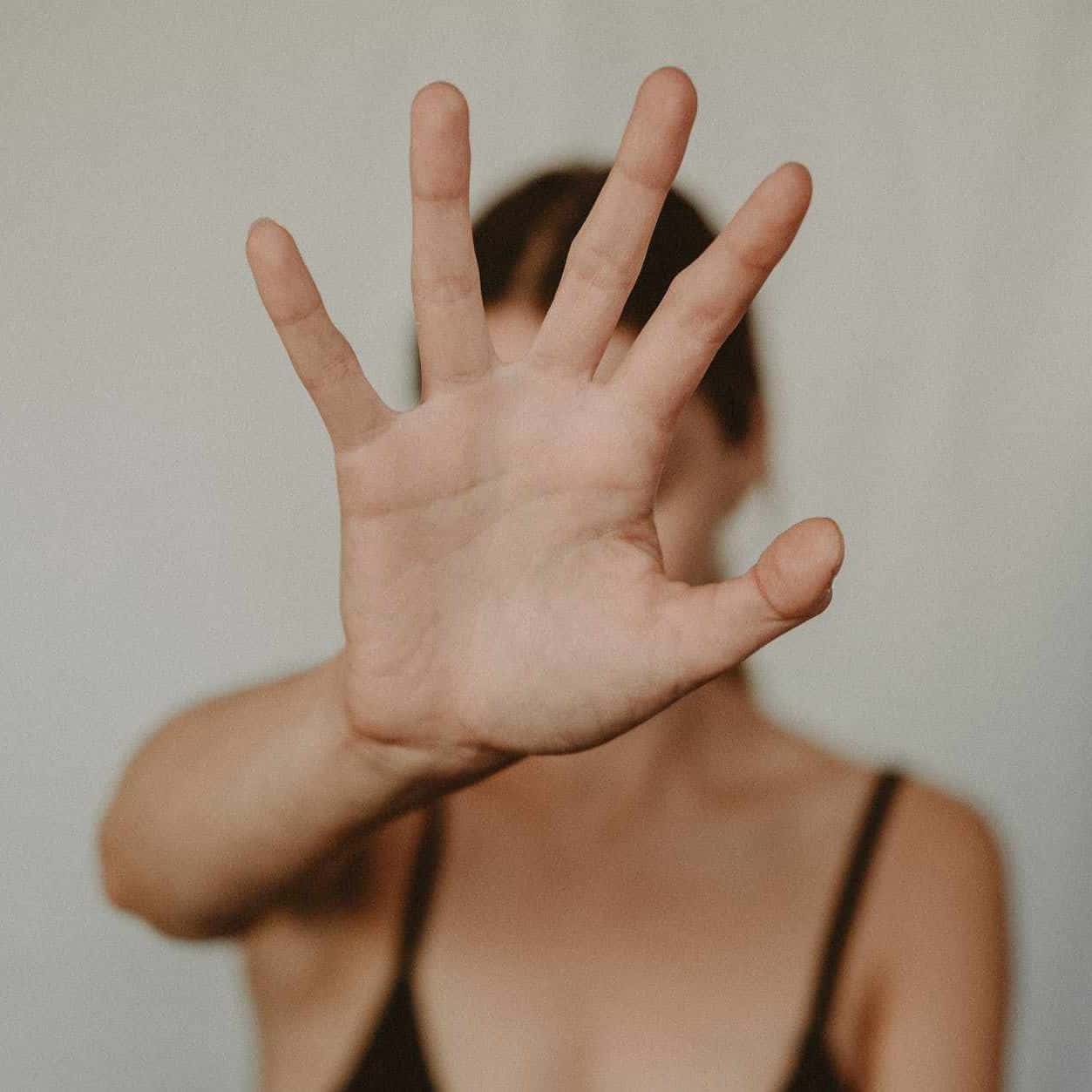 a woman from a previously abusive relationship holding one hand up defensively